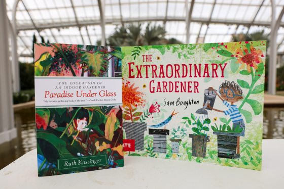 Two colorful books about gardening, propped on display inside a conservatory.  